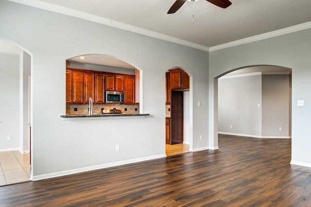 unfurnished living room featuring dark wood-type flooring, ceiling fan, and ornamental molding