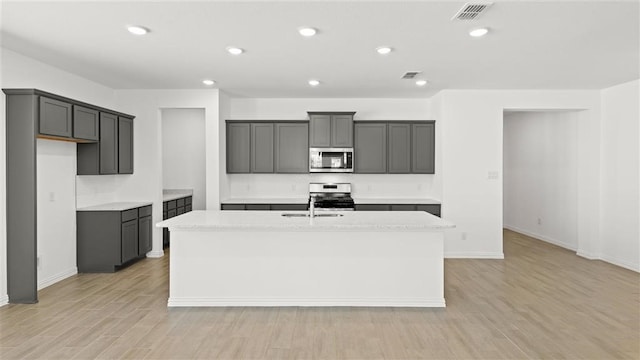 kitchen with a kitchen island with sink, appliances with stainless steel finishes, and gray cabinetry