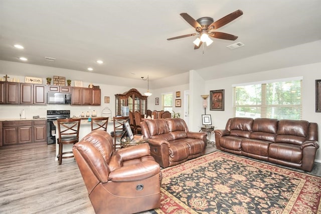 living room with light wood-type flooring, ceiling fan, and sink