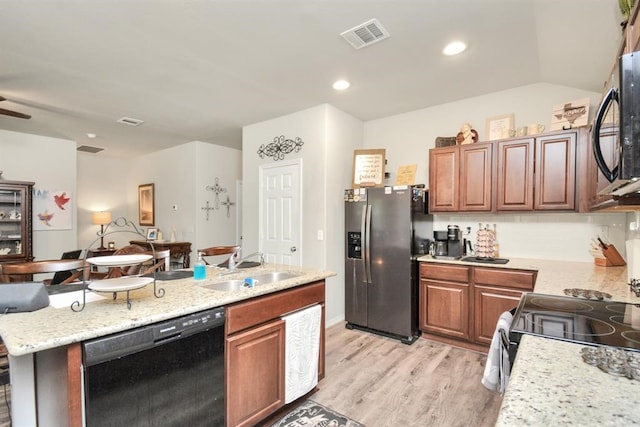 kitchen with light hardwood / wood-style floors, sink, appliances with stainless steel finishes, a kitchen island with sink, and lofted ceiling