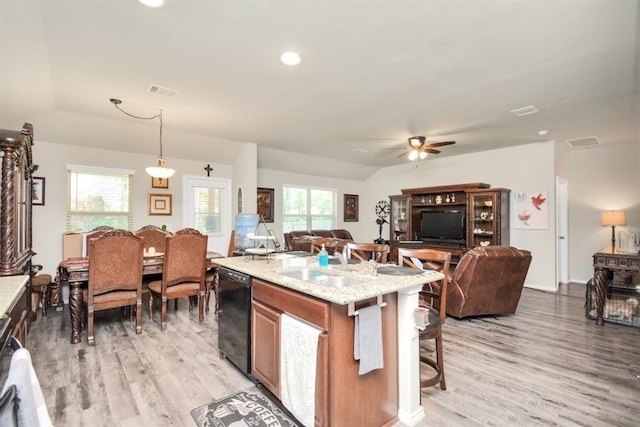 kitchen featuring dishwasher, plenty of natural light, hanging light fixtures, and light stone counters