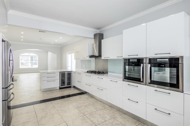 kitchen featuring white cabinetry, stainless steel appliances, wall chimney range hood, beverage cooler, and light tile patterned floors