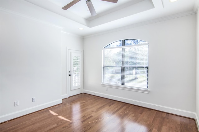 unfurnished room featuring a tray ceiling, ceiling fan, crown molding, and hardwood / wood-style flooring