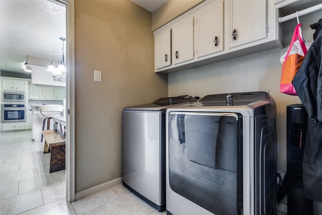 washroom featuring cabinets, an inviting chandelier, a textured ceiling, light tile patterned floors, and independent washer and dryer