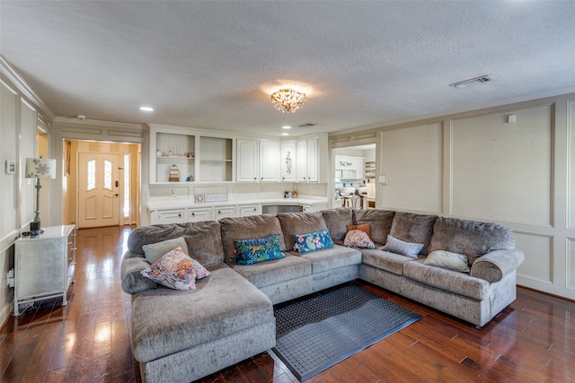 living room featuring dark hardwood / wood-style flooring, a textured ceiling, and ornamental molding