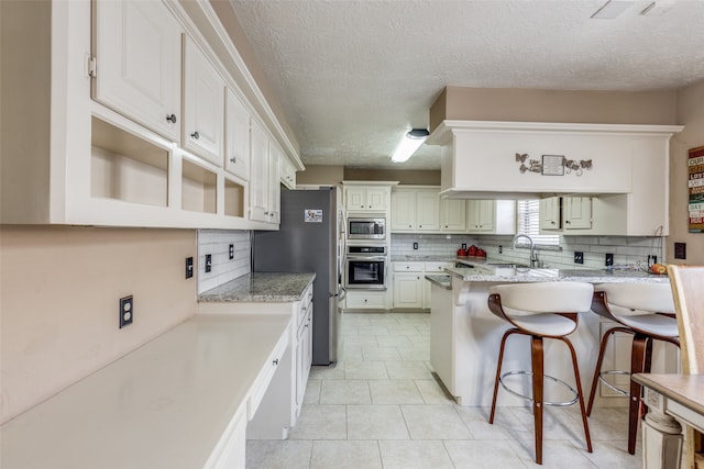 kitchen with white cabinets, a kitchen breakfast bar, stainless steel appliances, and kitchen peninsula