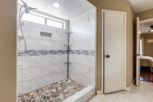 bathroom with tile patterned flooring, tiled shower, a textured ceiling, and ceiling fan