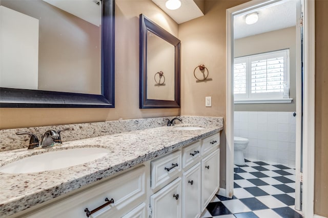 bathroom featuring vanity, tile walls, and toilet