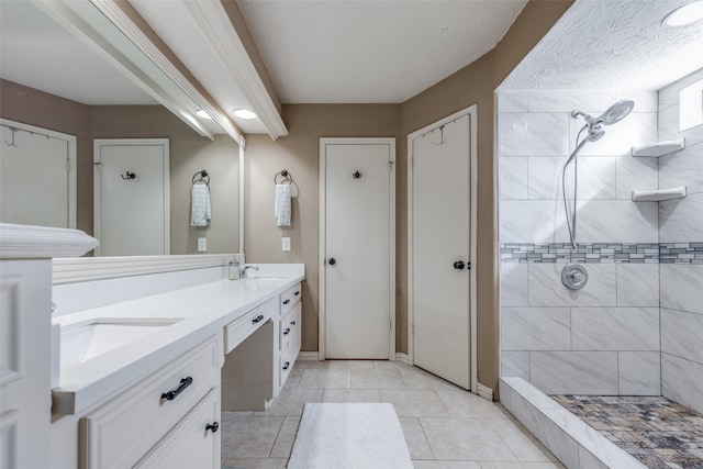 bathroom with vanity, a textured ceiling, tile patterned flooring, and tiled shower