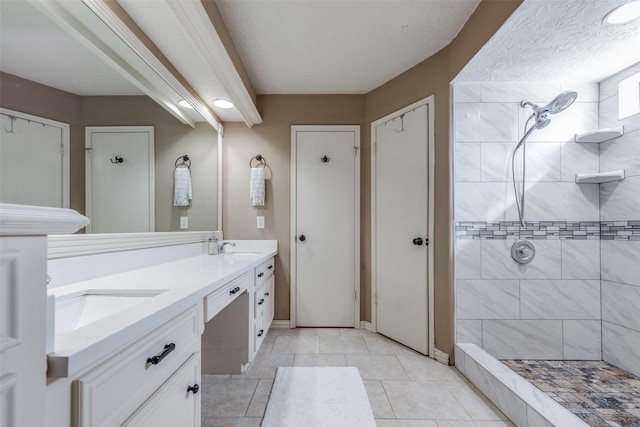 bathroom featuring vanity, tile patterned flooring, and a tile shower