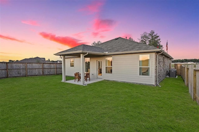 back house at dusk with a lawn and a patio