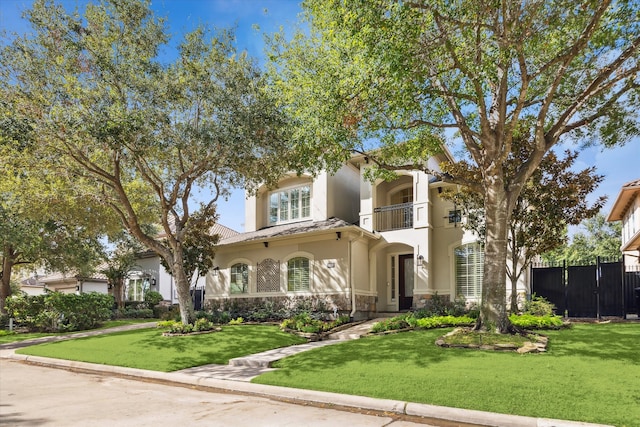 mediterranean / spanish-style house with a front lawn and a balcony