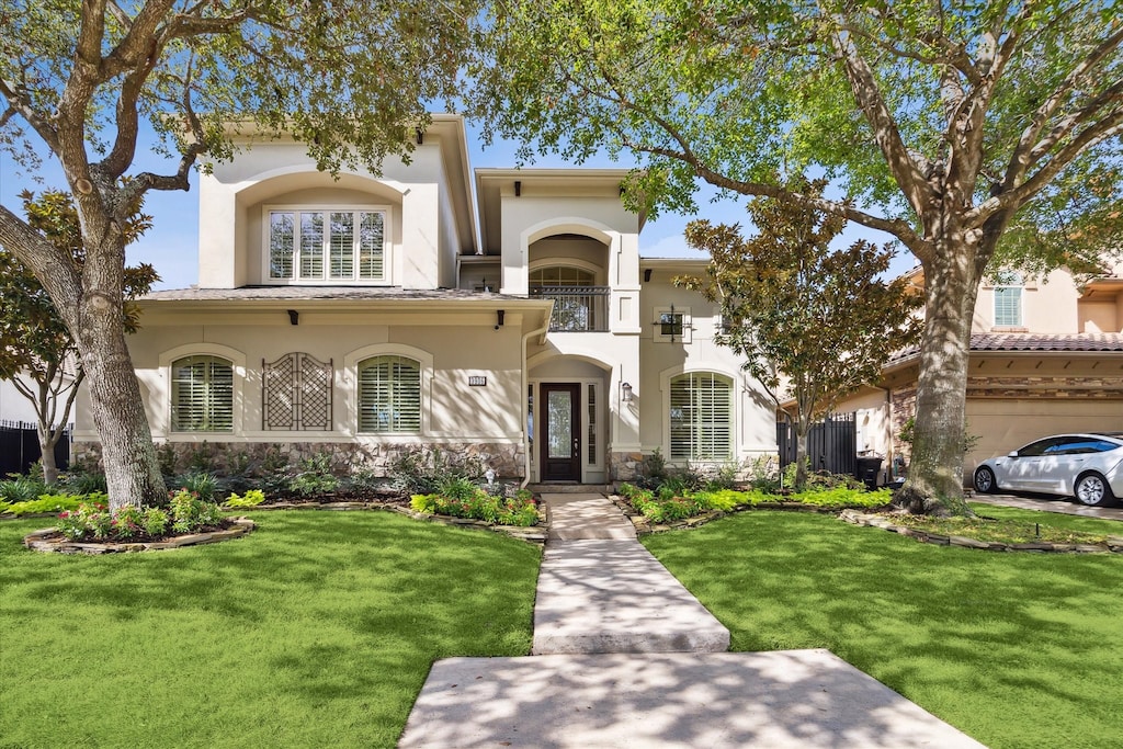 mediterranean / spanish-style house featuring a front lawn and a balcony