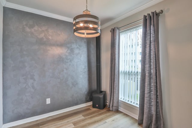 empty room featuring light wood-type flooring, a chandelier, and crown molding