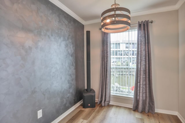 unfurnished room with crown molding, a notable chandelier, a healthy amount of sunlight, and light hardwood / wood-style flooring