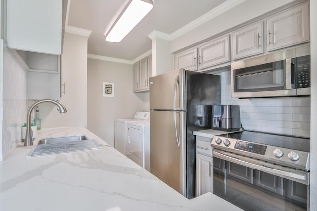 kitchen with separate washer and dryer, sink, ornamental molding, backsplash, and appliances with stainless steel finishes