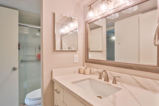 bathroom featuring a shower with door, vanity, and toilet