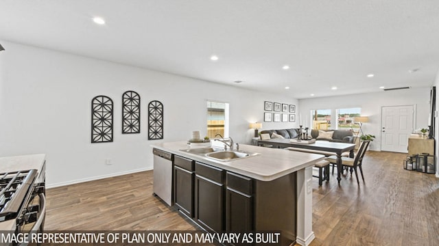 kitchen with appliances with stainless steel finishes, sink, a center island with sink, and wood-type flooring