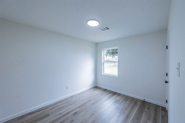 empty room with hardwood / wood-style flooring and a textured ceiling