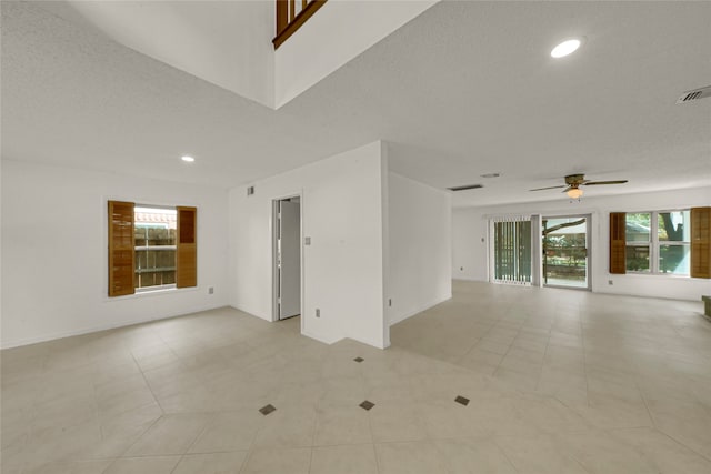 unfurnished room featuring a textured ceiling, light tile patterned floors, and ceiling fan