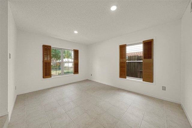 empty room with a textured ceiling and light tile patterned floors