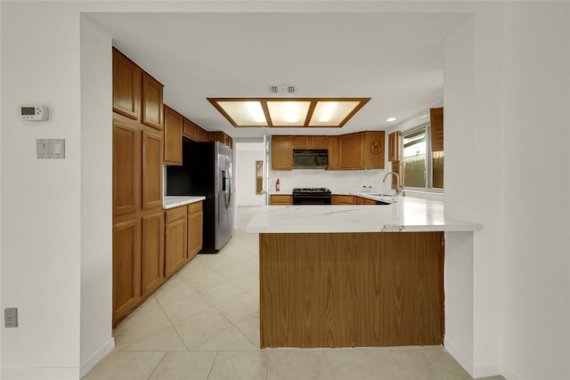 kitchen featuring sink, black appliances, kitchen peninsula, light tile patterned floors, and decorative backsplash