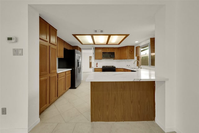 3327 Larkwood Ln, Sugar Land, TX 77479 - kitchen with black microwave, gas range, a sink, stainless steel refrigerator with ice dispenser, and a peninsula