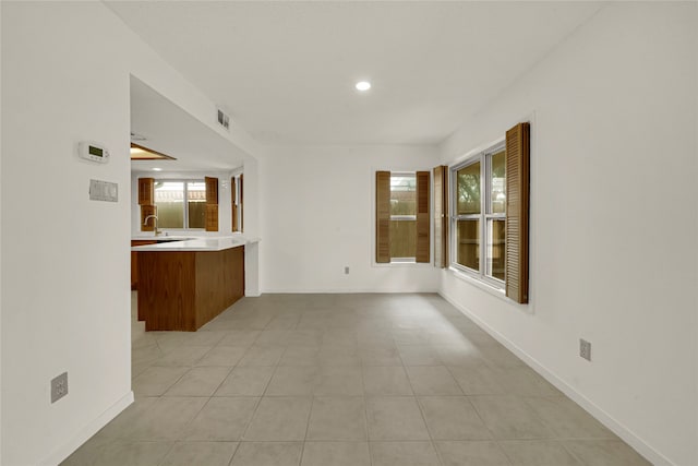 unfurnished living room featuring a wealth of natural light, sink, and light tile patterned floors