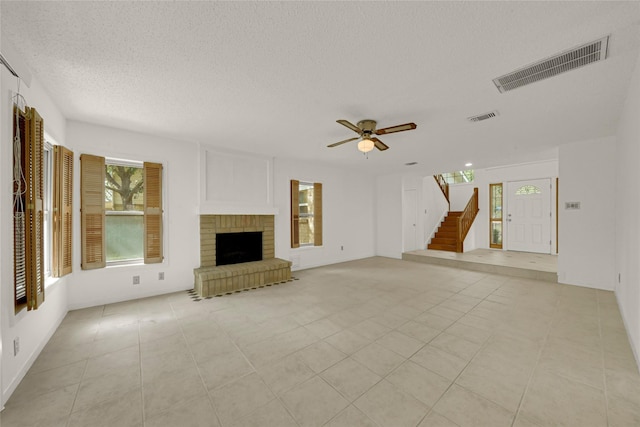 3327 Larkwood Ln, Sugar Land, TX 77479 - unfurnished living room featuring plenty of natural light, a textured ceiling, stairs, a ceiling fan, and a fireplace
