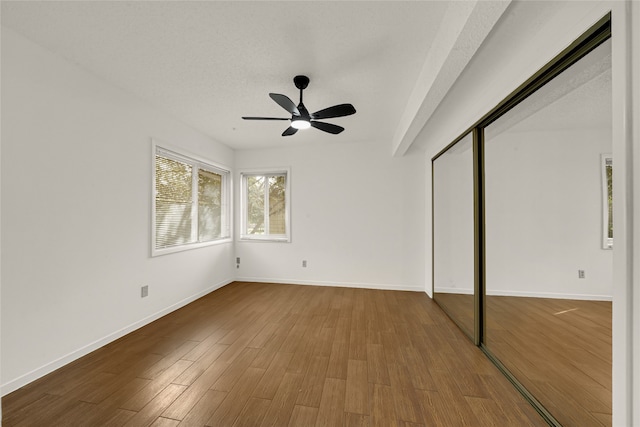 unfurnished bedroom featuring hardwood / wood-style flooring, ceiling fan, a textured ceiling, and a closet