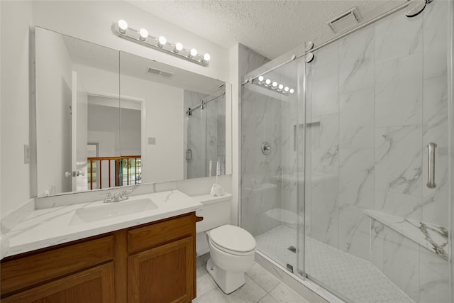 bathroom featuring a shower with door, vanity, a textured ceiling, tile patterned flooring, and toilet