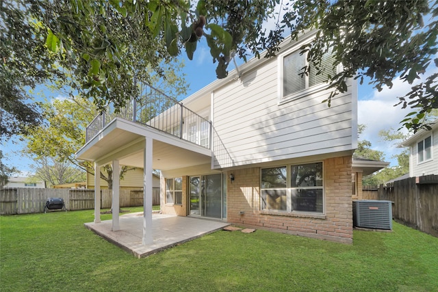 rear view of property featuring central AC unit, a patio, a lawn, and a balcony