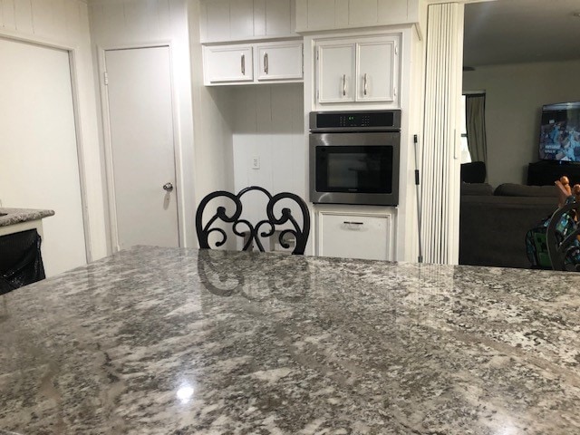 kitchen featuring white cabinets, stone counters, and stainless steel oven