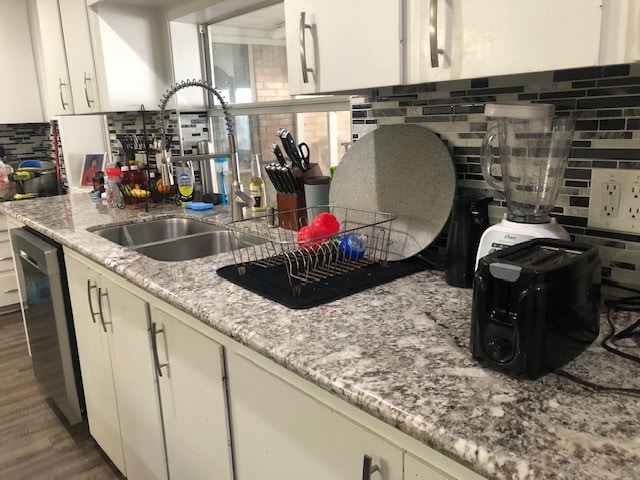 kitchen with decorative backsplash, stainless steel dishwasher, sink, and dark hardwood / wood-style floors