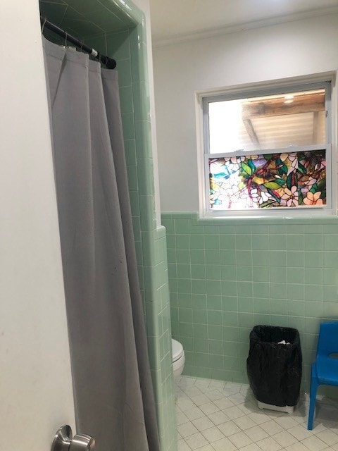 bathroom with a shower with curtain, tile patterned floors, toilet, and tile walls