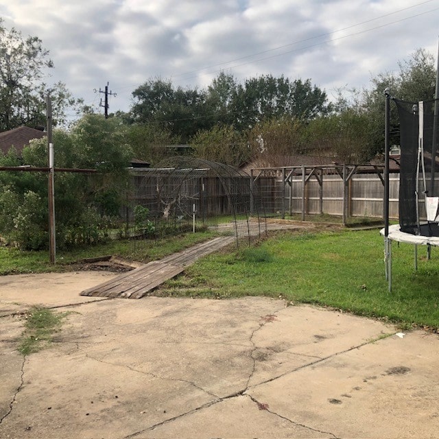 view of yard with a trampoline and a patio