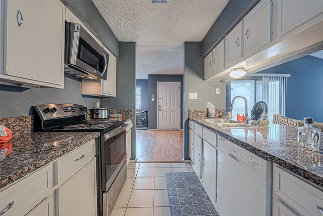 kitchen featuring white cabinetry, sink, appliances with stainless steel finishes, a textured ceiling, and light wood-type flooring