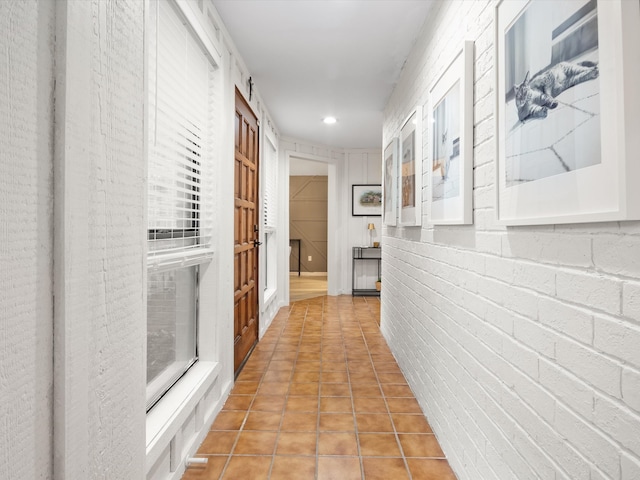 hallway with light tile patterned floors and brick wall