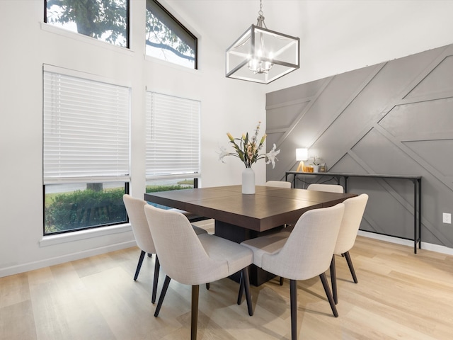 dining room with light hardwood / wood-style floors, a high ceiling, and a notable chandelier