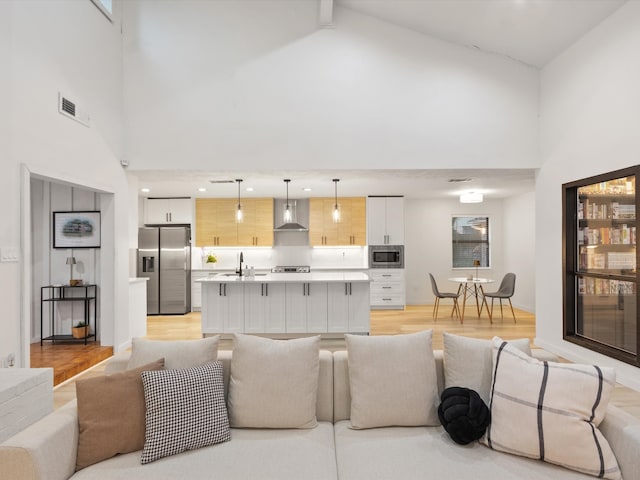 living room featuring beamed ceiling, sink, light hardwood / wood-style flooring, and high vaulted ceiling