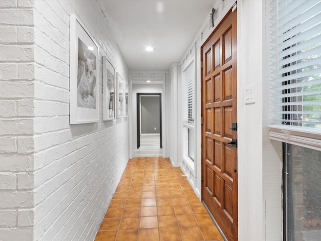 hallway with tile patterned flooring and brick wall