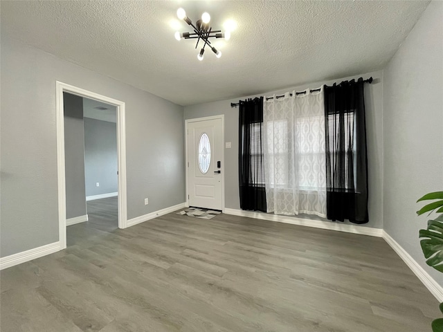 entrance foyer with an inviting chandelier, wood-type flooring, and a textured ceiling