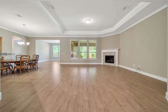 living room with hardwood / wood-style floors, a tile fireplace, a raised ceiling, and ornamental molding