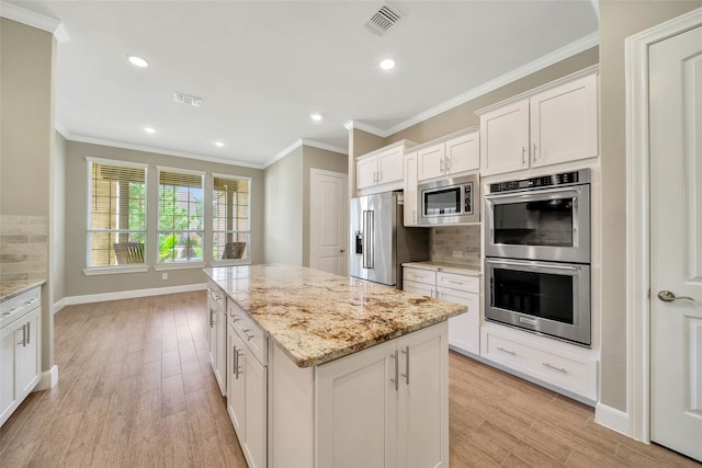 kitchen with stainless steel appliances, white cabinetry, light stone counters, a kitchen island, and light wood-type flooring