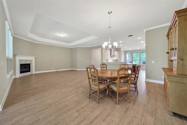 dining room featuring a chandelier, a tray ceiling, light wood-type flooring, and ornamental molding