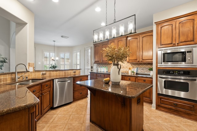 kitchen featuring stainless steel appliances, a notable chandelier, pendant lighting, sink, and kitchen peninsula