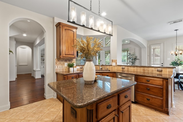 kitchen featuring a chandelier, sink, a kitchen island, pendant lighting, and light wood-type flooring