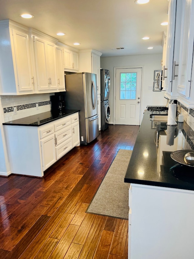 2817 Houston Ave, Houston, TX 77009 - kitchen featuring stacked washing machine and dryer, dark countertops, white cabinets, backsplash, and recessed lighting