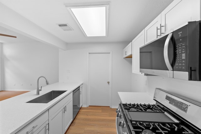 kitchen featuring appliances with stainless steel finishes, sink, light hardwood / wood-style floors, and white cabinets