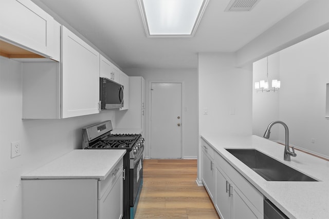 kitchen featuring pendant lighting, appliances with stainless steel finishes, sink, and white cabinets